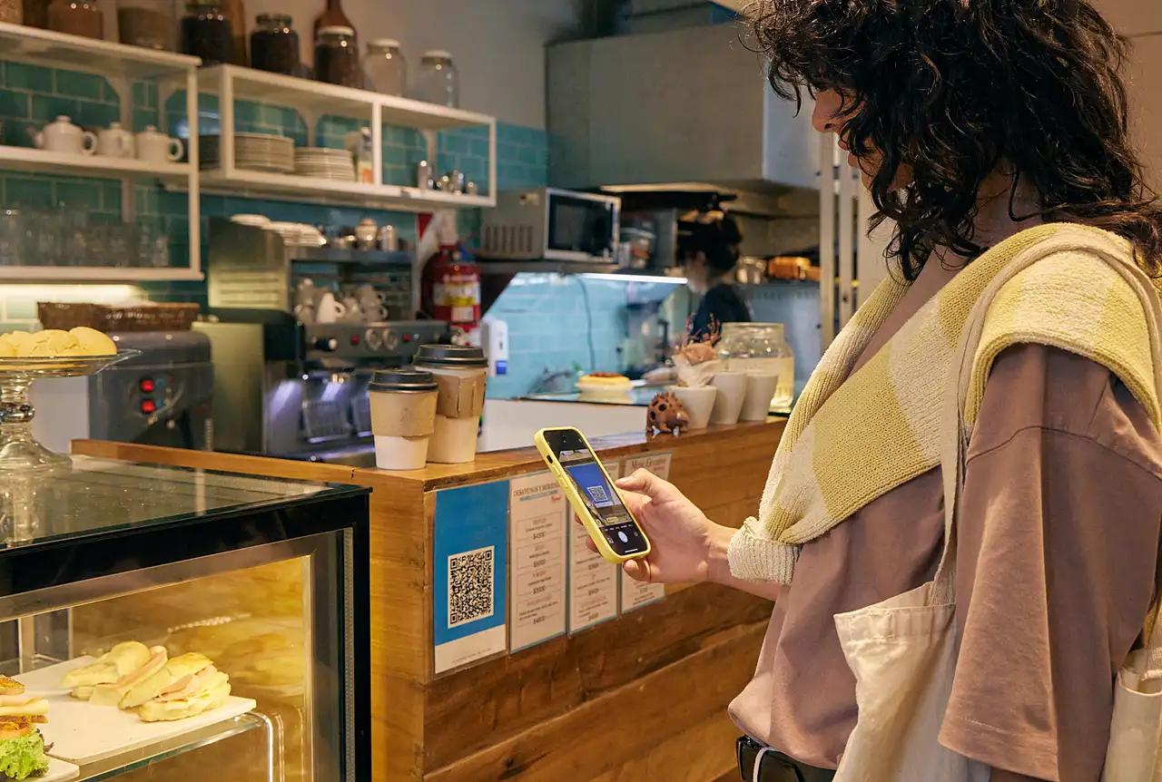 Clienta escaneando el QR de kato en el mostrador de un café