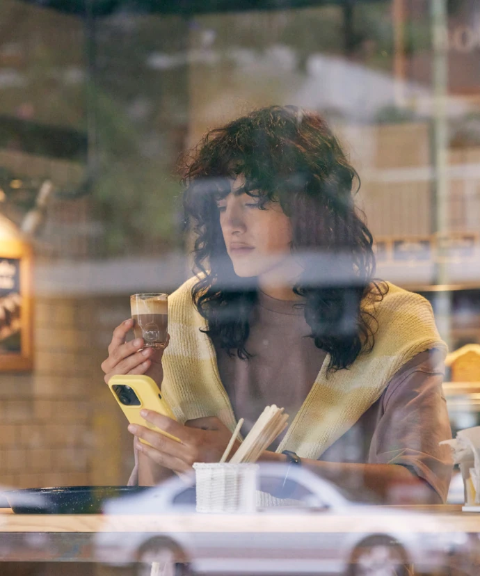 Clienta con su café y el celular en la mesa de una cafetería